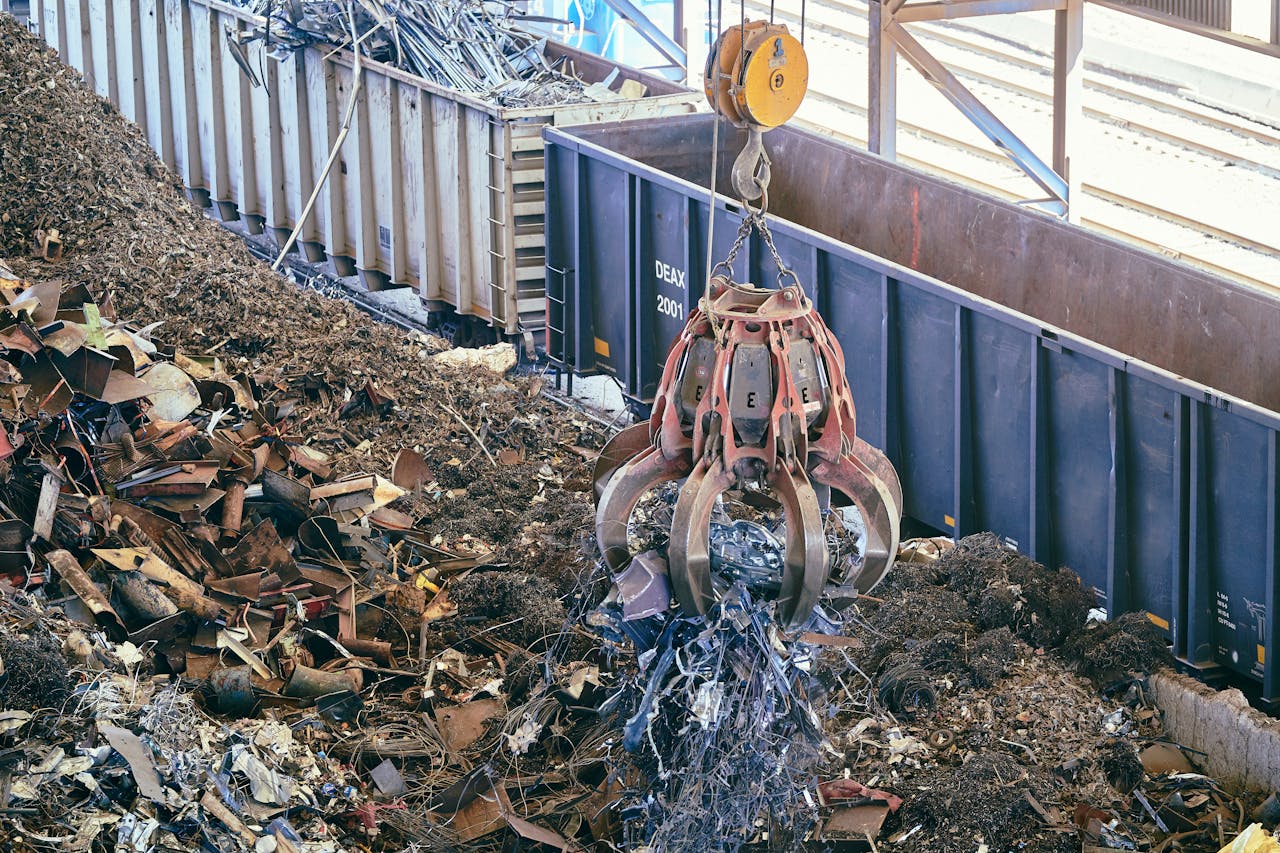 A claw crane lifting scrap metal in an industrial recycling facility.